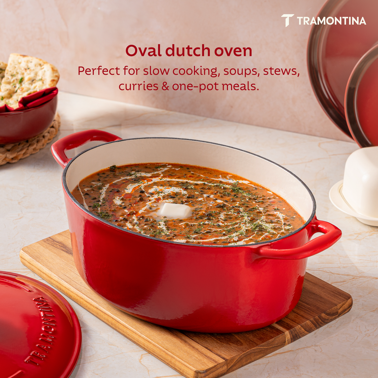 Tramontina India Bestow enameled cast iron oval Dutch oven in gradated red, 6.6L, showing a smooth glossy exterior and sturdy handles.