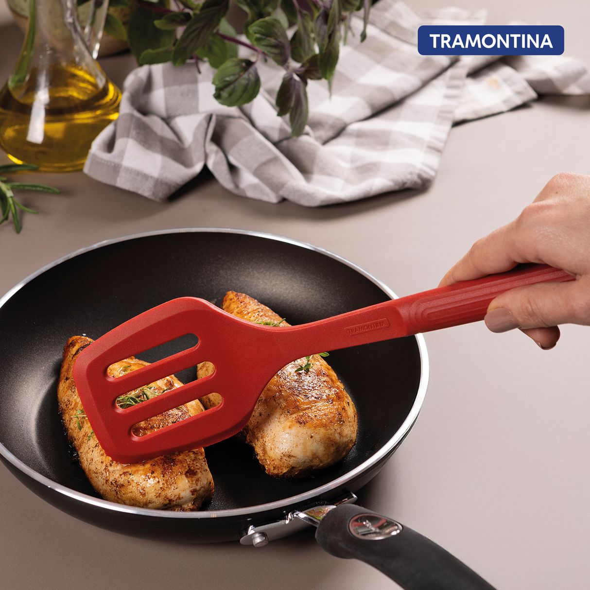 Red Tramontina India Softta Silicone Slotted Turner with ergonomic handle for flipping and serving food in the kitchen.