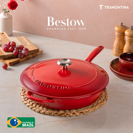 Tramontina India Bestow 25cm red enameled cast iron skillet with lid, showing the glossy red exterior and sturdy handle.