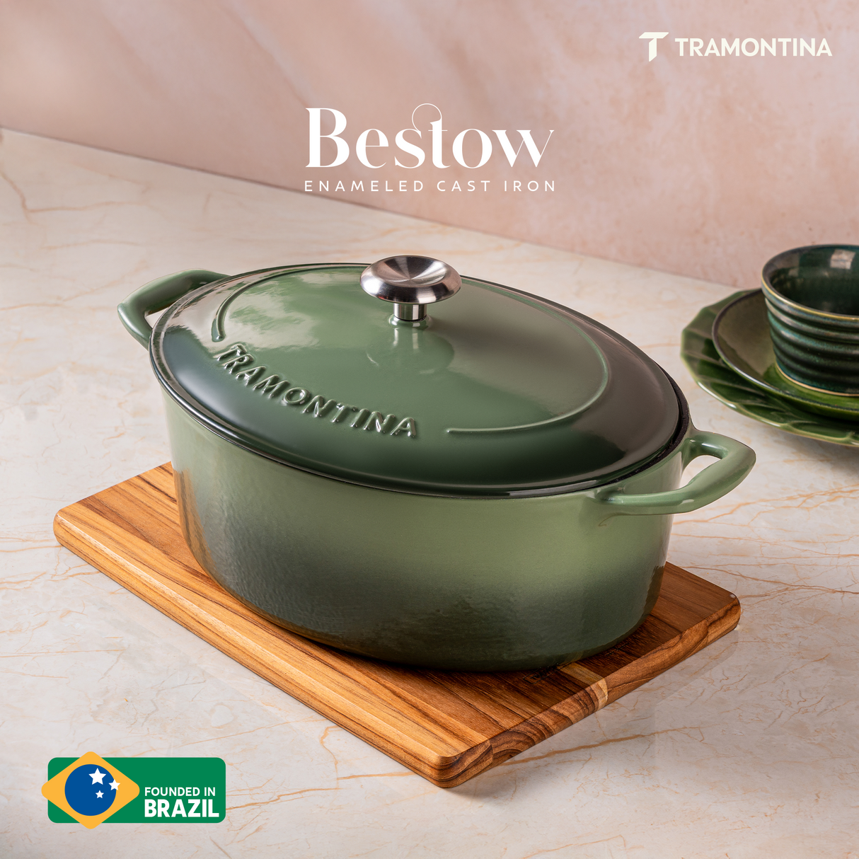 Tramontina India Bestow enameled cast iron oval Dutch oven in cactus green, 6.6L, shown in a kitchen setting with lid on.