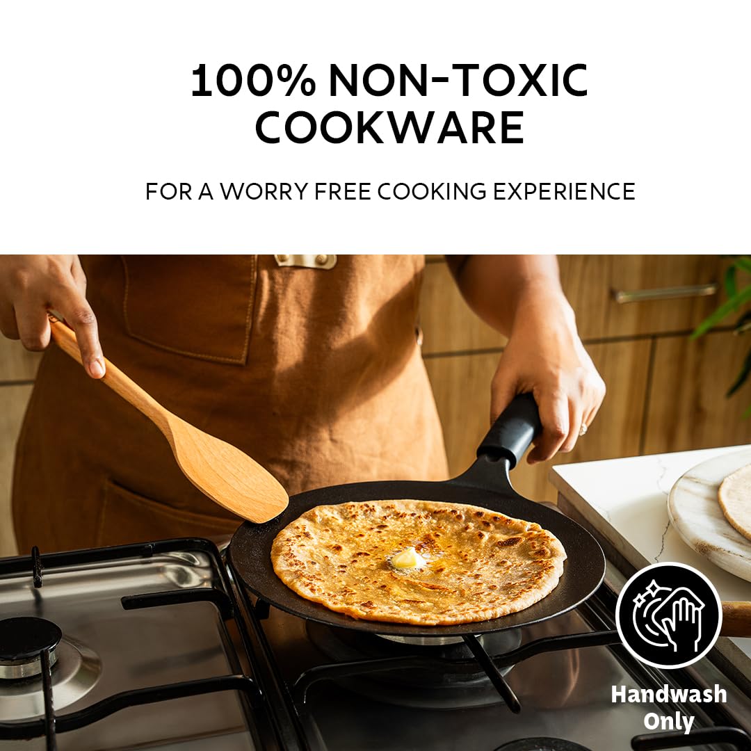 Tramontina India 26cm pre-seasoned cast iron concave roti tawa with heat-resistant silicone grip on a kitchen countertop.